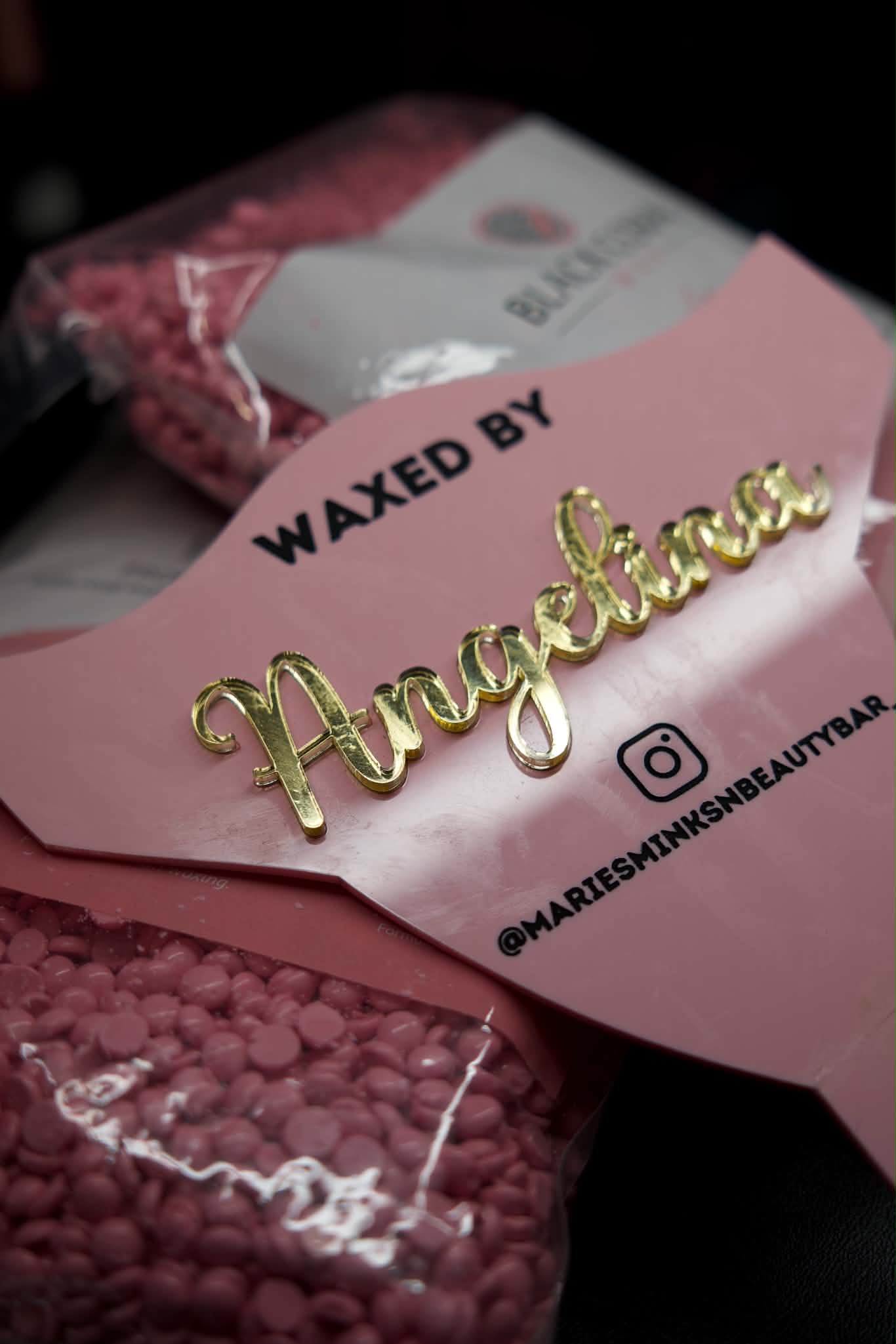 Pink Waxed by Angelina sign displayed over bags of pink wax beads
