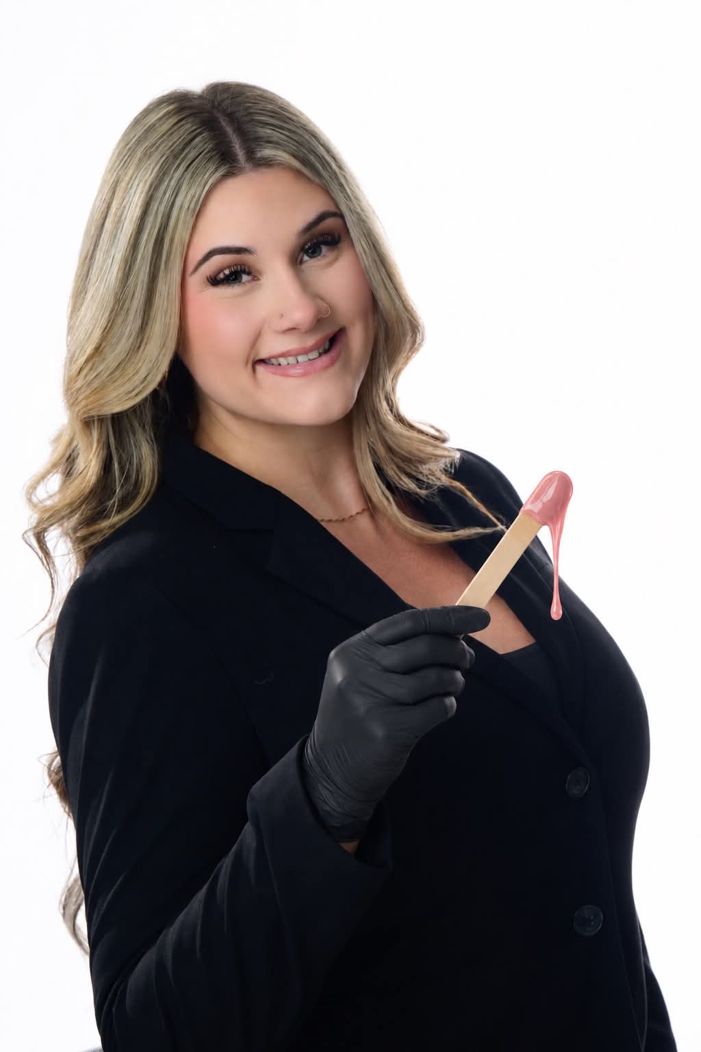Angelina wearing a black glove and holding a wooden waxing stick with pink wax